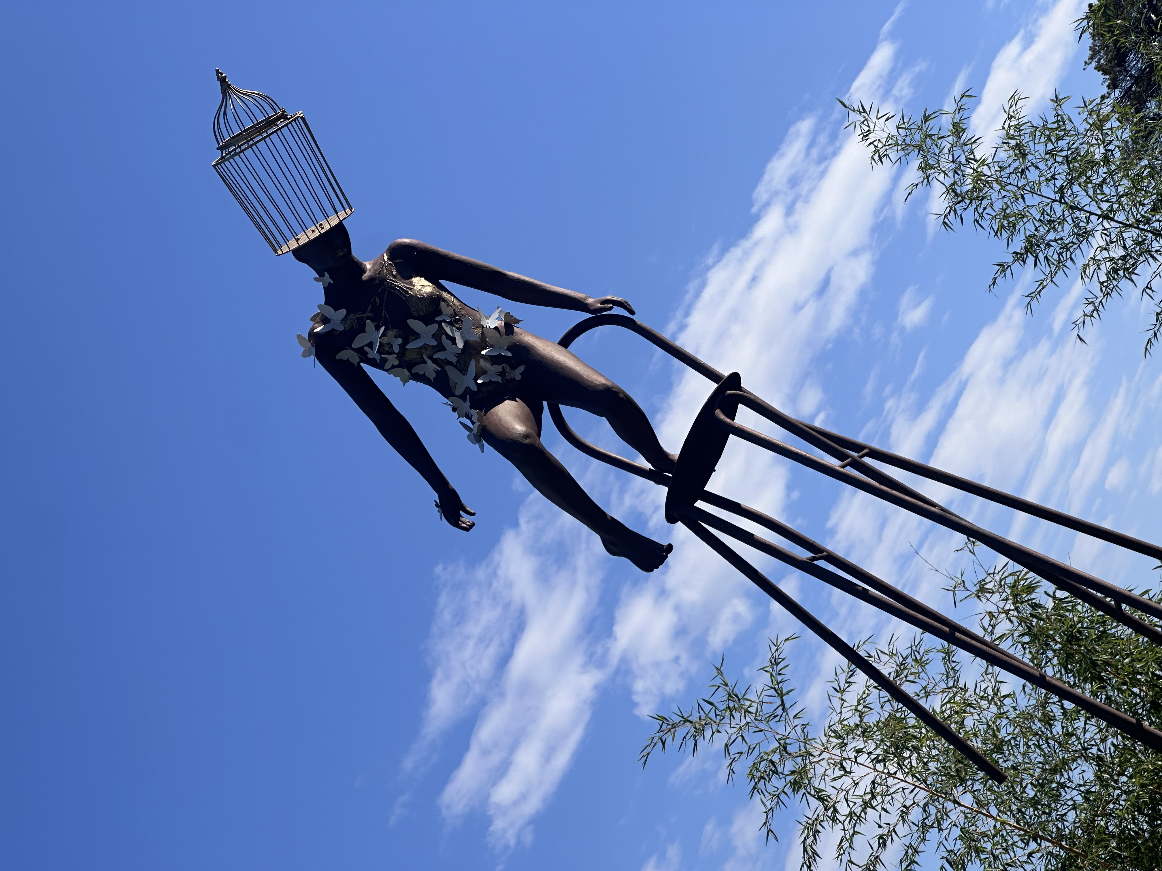 Équi-Libre — monumental bronze sculpture by George, a woman with a birdcage head balanced on a high perch, homage to Jean-Michel Folon